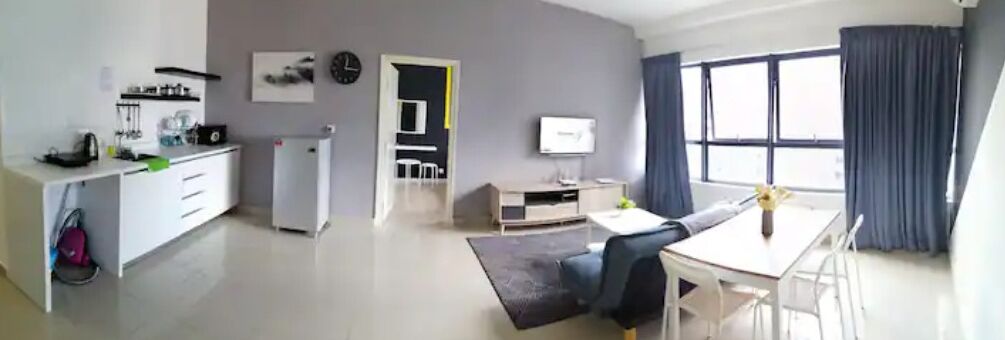 A modern living room with a dining area, a kitchen, and a small office space.