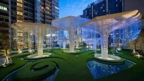 Une structure architecturale moderne, agrémentée d’éléments lumineux et de jeux d’eau, située dans un environnement urbain.