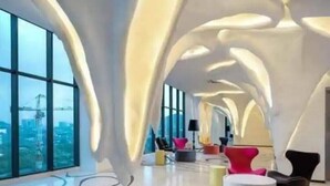 Un intérieur moderne avec un plafond incurvé, de grandes fenêtres et des meubles contemporains.