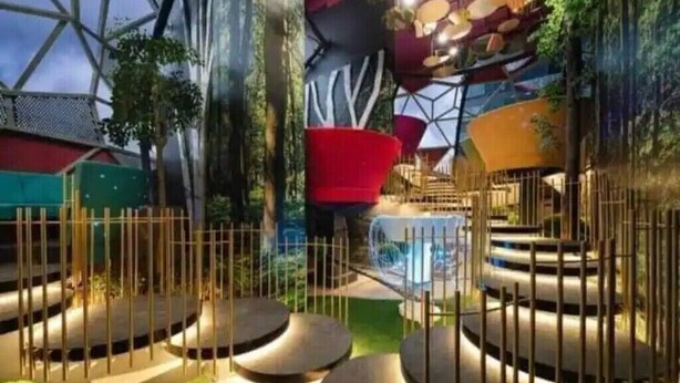 Un design architectural moderne et géométrique, avec une structure centrale de couleur rouge, entourée d’une clôture et agrémentée de différents espaces d’assise.
