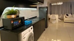 A modern kitchen with a built-in washing machine, a microwave, and a sink. - Signature Premium Suite KLCC Arte+ 2R2B (Kuala Lumpur)