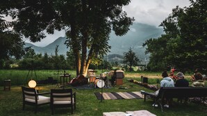 An outdoor seating area with chairs and a bench, surrounded by trees and a view of mountains. - Hostal Cal Franciscó (Gosol)