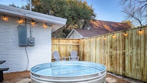 A backyard with a hot tub, two Adirondack chairs, a wooden fence, and a white building with a brick wall. - 5mins to Kyle Field, 5BR w Private Backyard & Pool (Bryan)