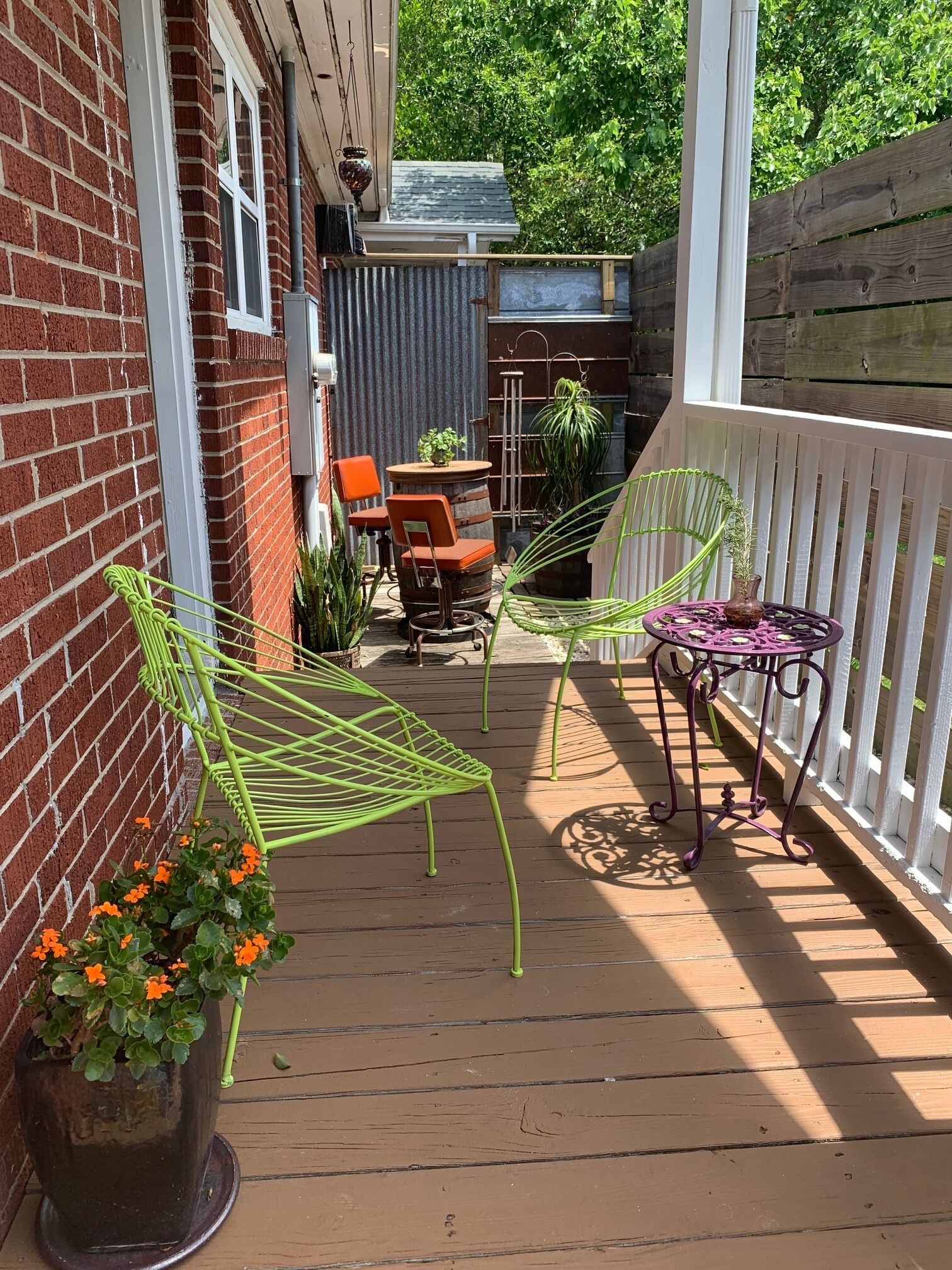 A covered patio with a brick wall, outdoor seating, and potted plants.