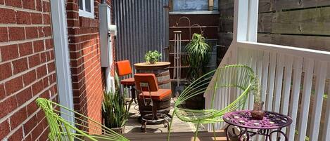 A covered patio with a brick wall, outdoor seating, and potted plants.