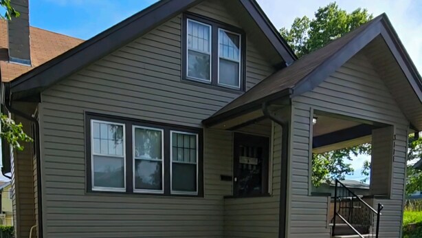 A two-story house with a covered porch and a small staircase leading to the upper level.