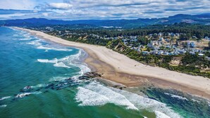Un pueblo costero con playa, casas y montañas al fondo.