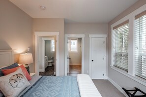 A bedroom with a bed, a nightstand, a lamp, and a window with blinds.