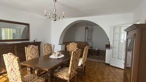 A dining room with a large table and six chairs, a chandelier, and a tiled floor. - Maison Traditionnelle en Campagne (Saint-Quentin-de-Caplong)