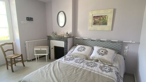 A bedroom with a bed, a chair, a desk, a radiator, a mirror, and a picture on the wall. - Maison Traditionnelle en Campagne (Saint-Quentin-de-Caplong)