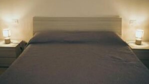 Un lit avec une tête de lit, deux tables de chevet avec des lampes et un mur peint dans une couleur neutre.