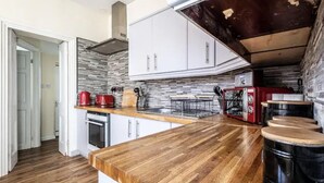 A kitchen with a wooden countertop, white cabinets, and a red toaster. - The Boat House Sleeps 4 Pet Friendly (Dawlish)