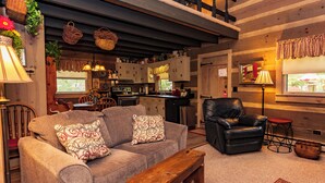 A cozy living room with a sofa, a leather chair, and a wooden bench. - Azalea Garden Inn (Blowing Rock)