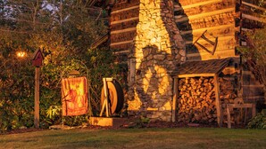 A rustic log cabin with a stone chimney, surrounded by trees and a well-maintained lawn. - Azalea Garden Inn (Blowing Rock)