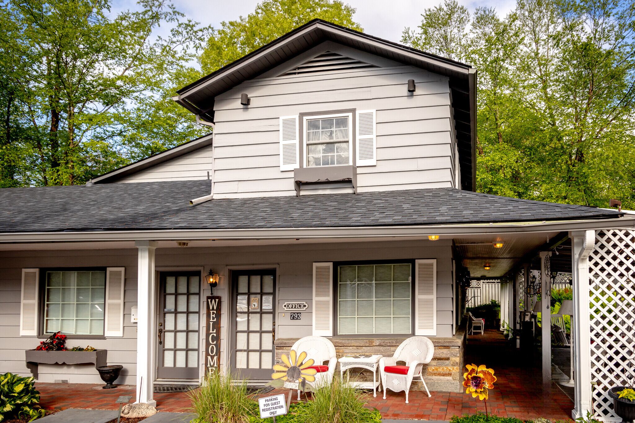 A two-story house with a porch, a welcome sign, and a mailbox.
