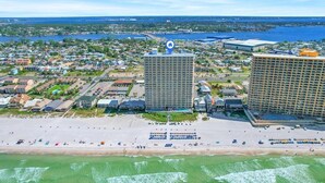 An aerial view of a coastal city with a beach, two prominent hotels, and a marina.