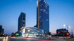 A modern high-rise building with a curved glass facade and a prominent vertical light strip. - Crowne Plaza Hangzhou Linping by IHG (Hangzhou)