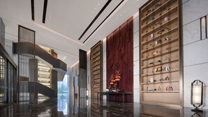 Eine moderne Lobby mit Marmorboden, einer Treppe und einem großen Bücherregal.