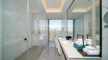 Un baño moderno con cabina de ducha de vidrio, un espejo grande y vistas a un paisaje urbano.