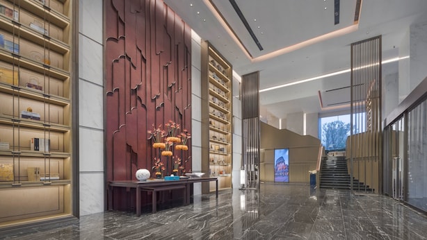 A modern lobby with a marble floor, bookshelves, a decorative wall, and a staircase. - Crowne Plaza Hangzhou Linping by IHG (Hangzhou)