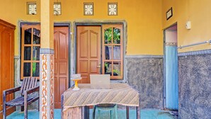 A room with a wooden table, a laptop, and a chair. There are two doors and a window with a view of greenery. - Hotel O Sekar Jagat Near Pantai Baluk Rening (Negara)