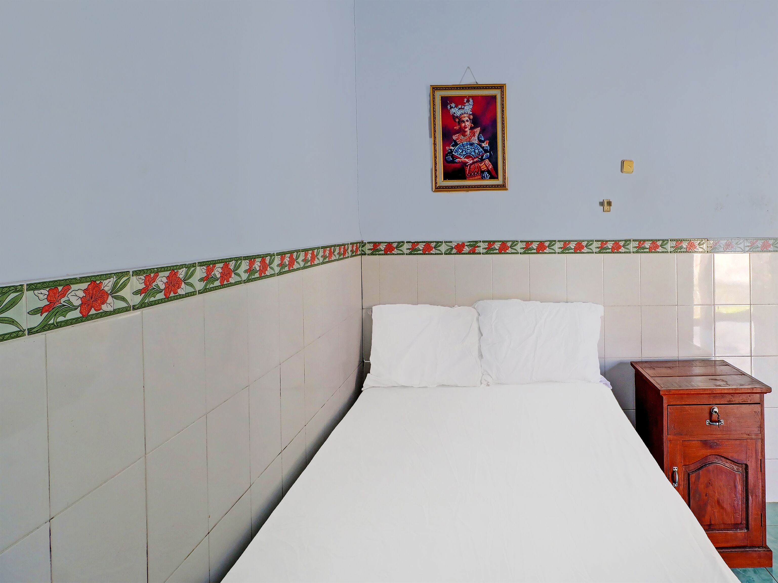 A room with a bed, a wooden cabinet, and a decorative border on the wall.