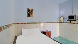 A bedroom with a bed, a small wooden dresser, a wall-mounted TV, and a framed picture. - Hotel O Sekar Jagat Near Pantai Baluk Rening (Negara)