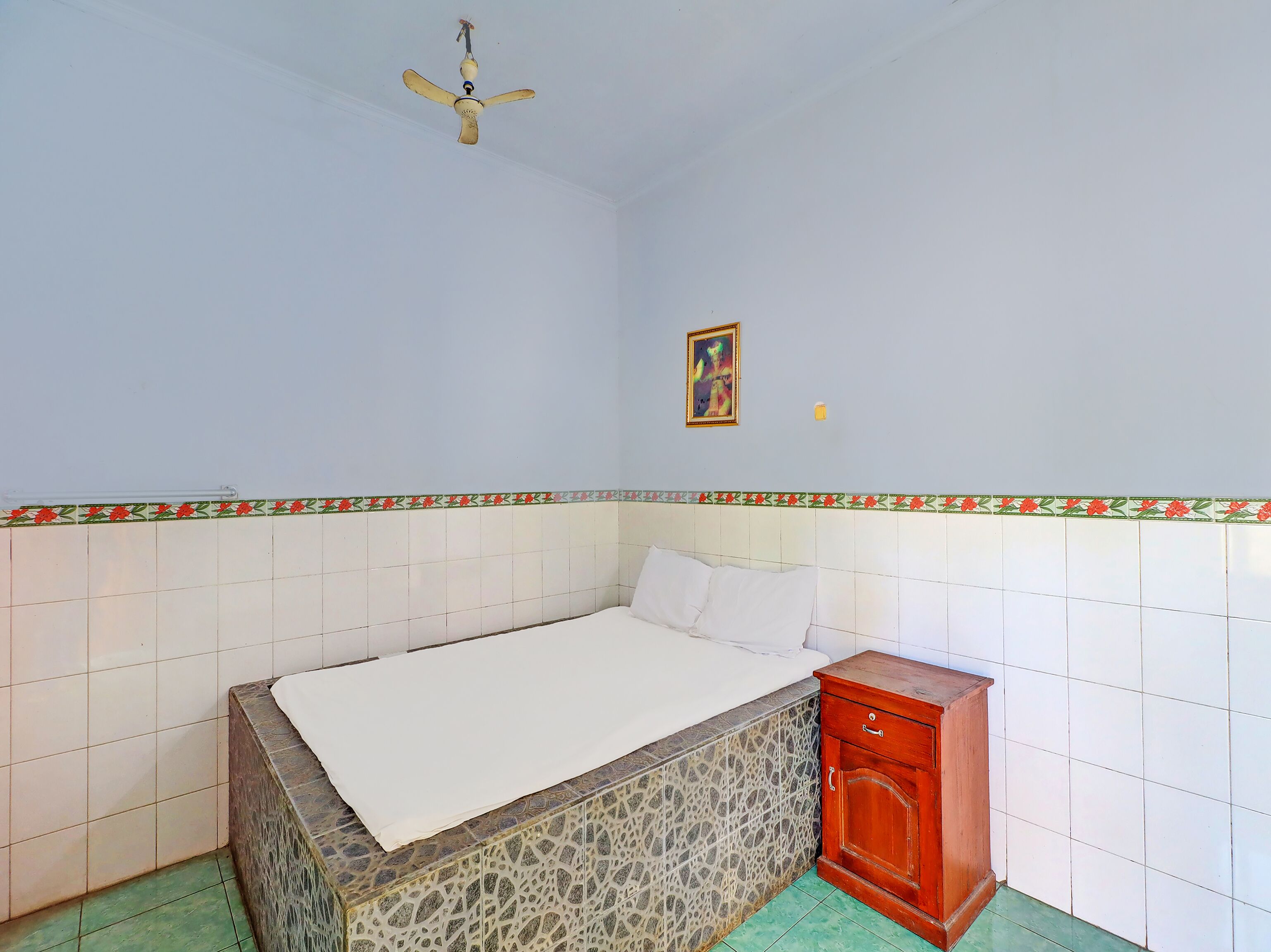 A bedroom with a bed, a wooden cabinet, a ceiling fan, and a decorative border on the wall.