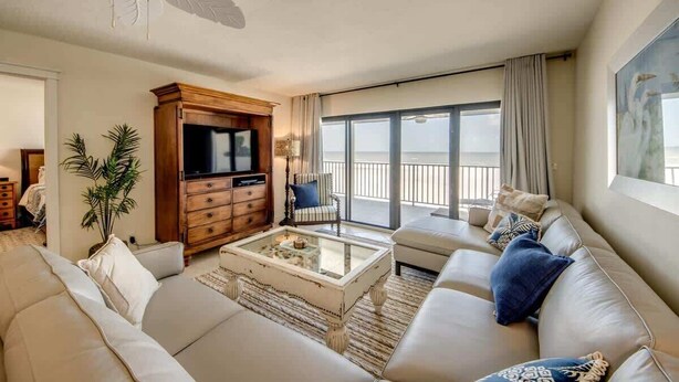 Un salon comprenant un canapé, une table basse, un téléviseur, un ventilateur de plafond et une vue sur la mer.