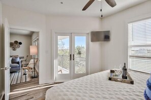 A bedroom with a large bed, a ceiling fan, a balcony door, and a view of the outdoors. - Santa Rosa Beach Getaway (Santa Rosa Beach)