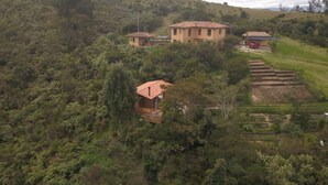 A rural house with a red-tiled roof surrounded by dense greenery and terraced fields. - El Respiro de La Colina (Tuta)