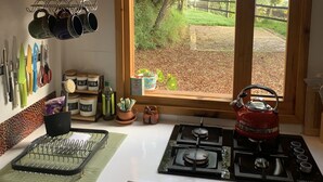 A kitchen with a large window, a stove, and various kitchen utensils and appliances. - El Respiro de La Colina (Tuta)