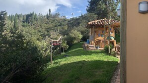 A small, rustic building with a tiled roof, surrounded by lush greenery and trees. - El Respiro de La Colina (Tuta)