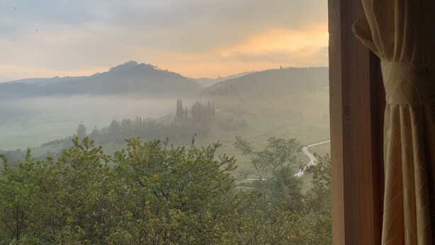 A view from a window overlooking a misty landscape with rolling hills and a road. - El Respiro de La Colina (Tuta)