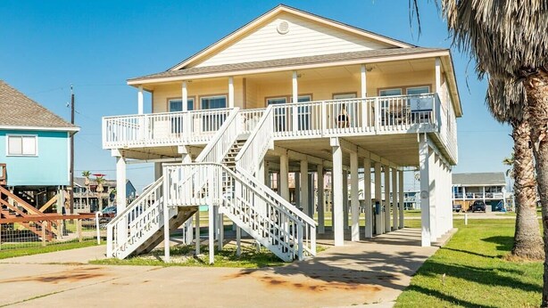 A two-story building with a balcony and a staircase leading to the upper level. - Banana Cabana – Gulf Views & Good Vibes (Surfside Beach)