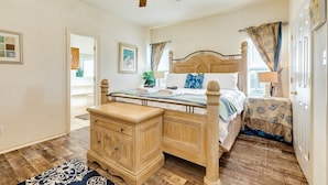 A bedroom with a wooden bed, a nightstand, a ceiling fan, and a view of the outside. - Banana Cabana – Gulf Views & Good Vibes (Surfside Beach)