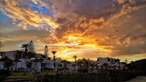 Ein Resort mit weißen Gebäuden, Palmen und Liegestühlen.