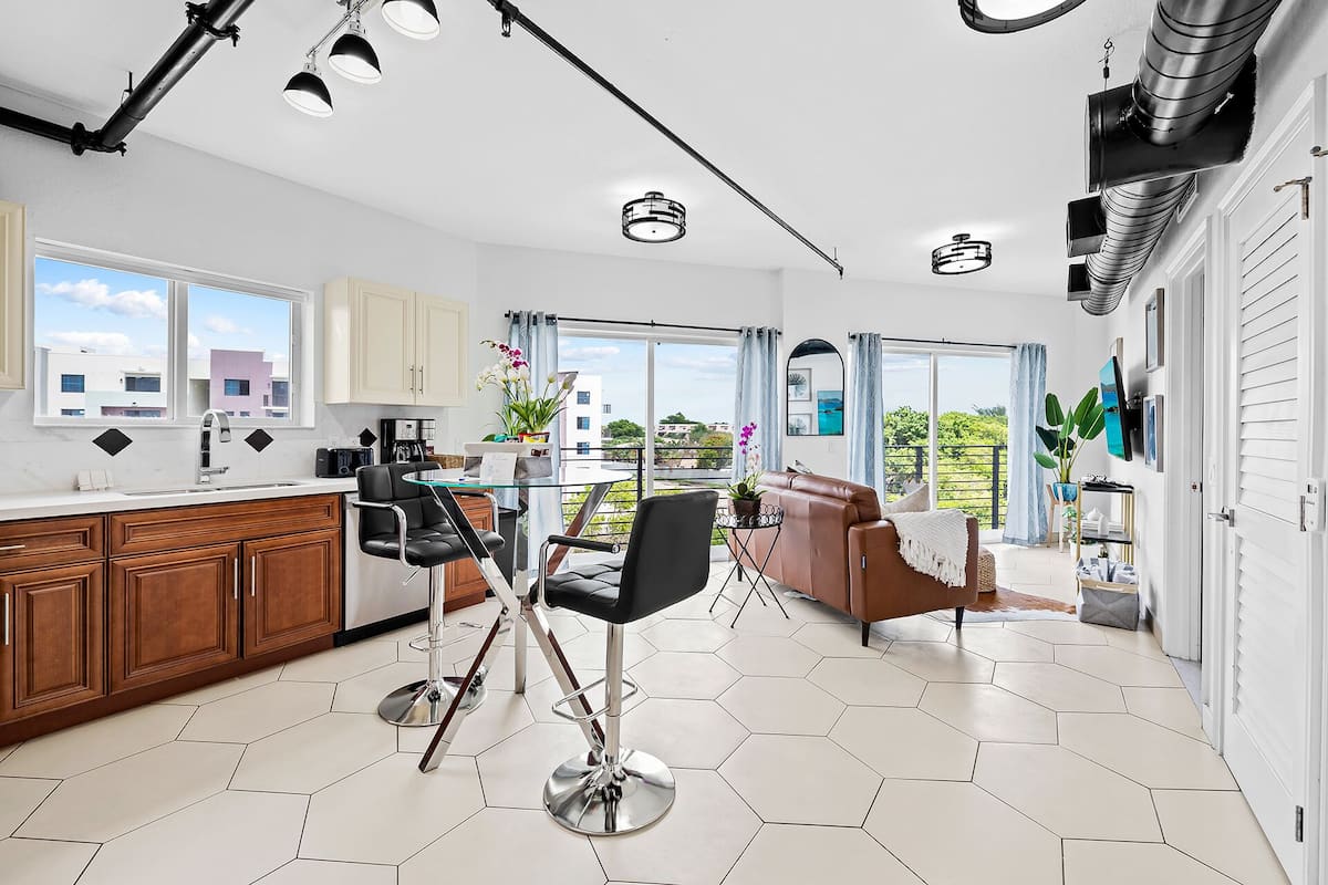 A modern kitchen with a dining area, large windows, and a view of the city.