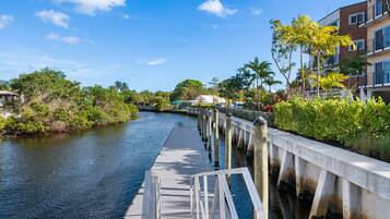 A waterfront walkway with a concrete barrier, a calm river, and lush greenery.