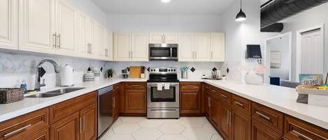 A modern kitchen with white cabinets, stainless steel appliances, and a hexagonal tile floor.