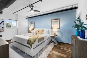 Un dormitorio moderno con una cama grande, lámparas de noche, un ventilador de techo y vistas al exterior.
