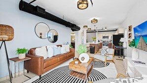 Una sala de estar moderna con un sofá de cuero marrón, una mesa de centro de madera y un tapete a rayas negras y blancas.