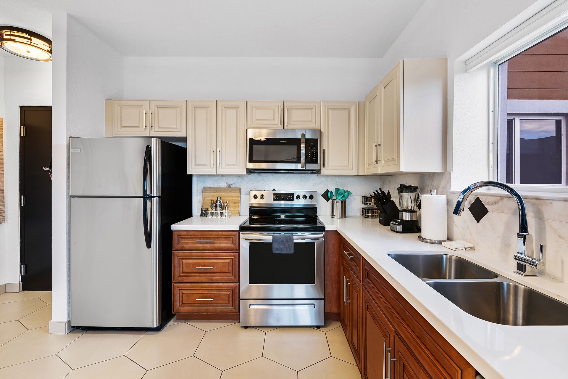 Una cocina moderna con electrodomésticos de acero inoxidable, armarios de madera y un amplio ventanal.