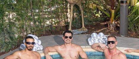 Three men in a swimming pool with a statue of a bird in the background.