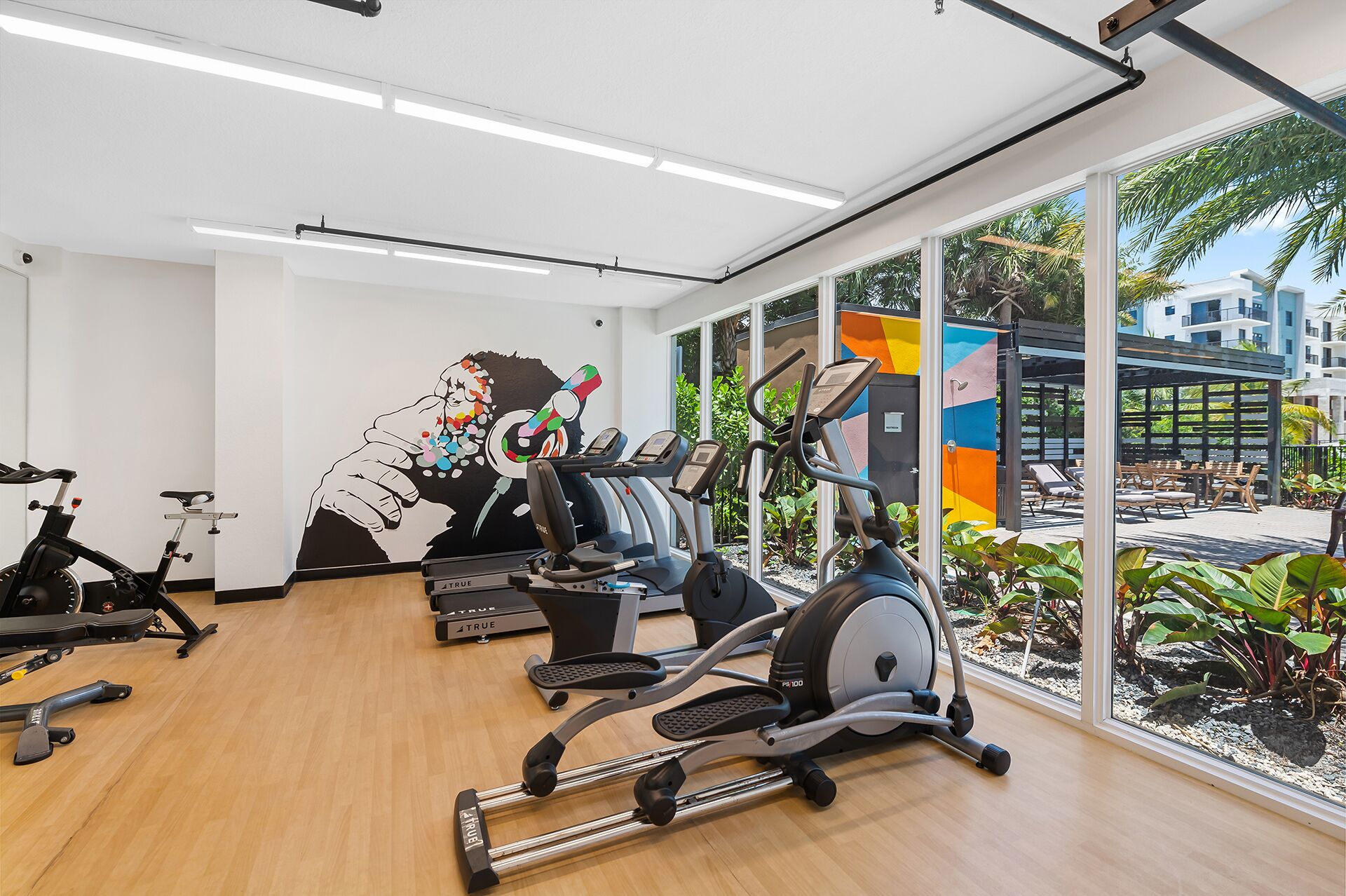 Un gimnasio con equipo de ejercicio, ventanas amplias y vistas al exterior.