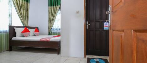 A room with a bed, a wooden door, and a tiled floor.