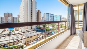 Un balcón con vistas a un paisaje urbano, que incluye edificios altos y una zona de piscina.