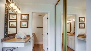 Un bagno con uno specchio grande, quadri appesi e un asciugamano sul ripiano.