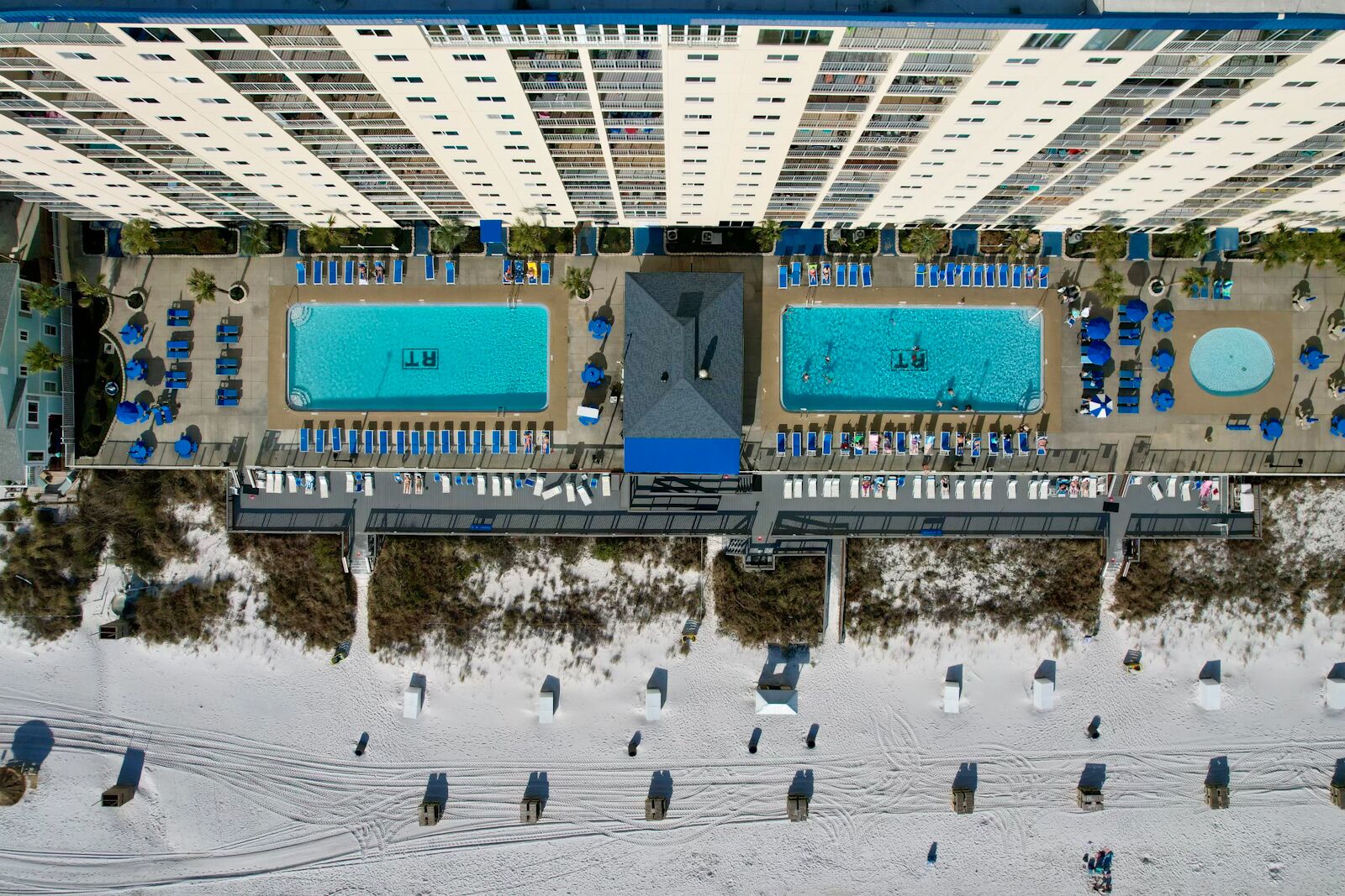 A resort with two swimming pools, a covered walkway, and beach huts.