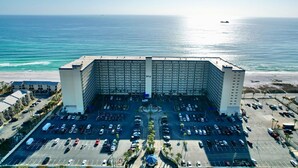 Un hotel grande con patio central y estacionamiento, con vista a una playa y al océano.